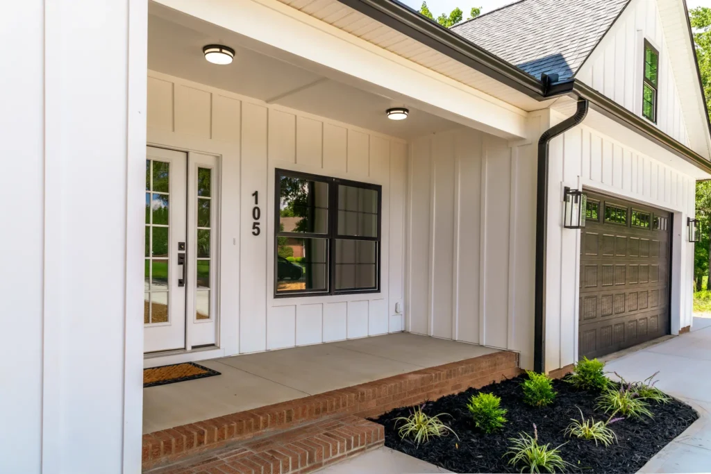 Custom home covered entry with a black-framed glass front door and board-and-batten siding
