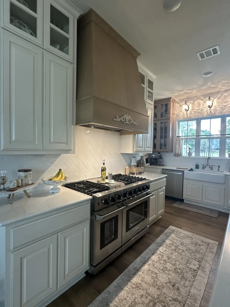 Custom home kitchen with sage-green cabinetry, a gas range and a vent hood
