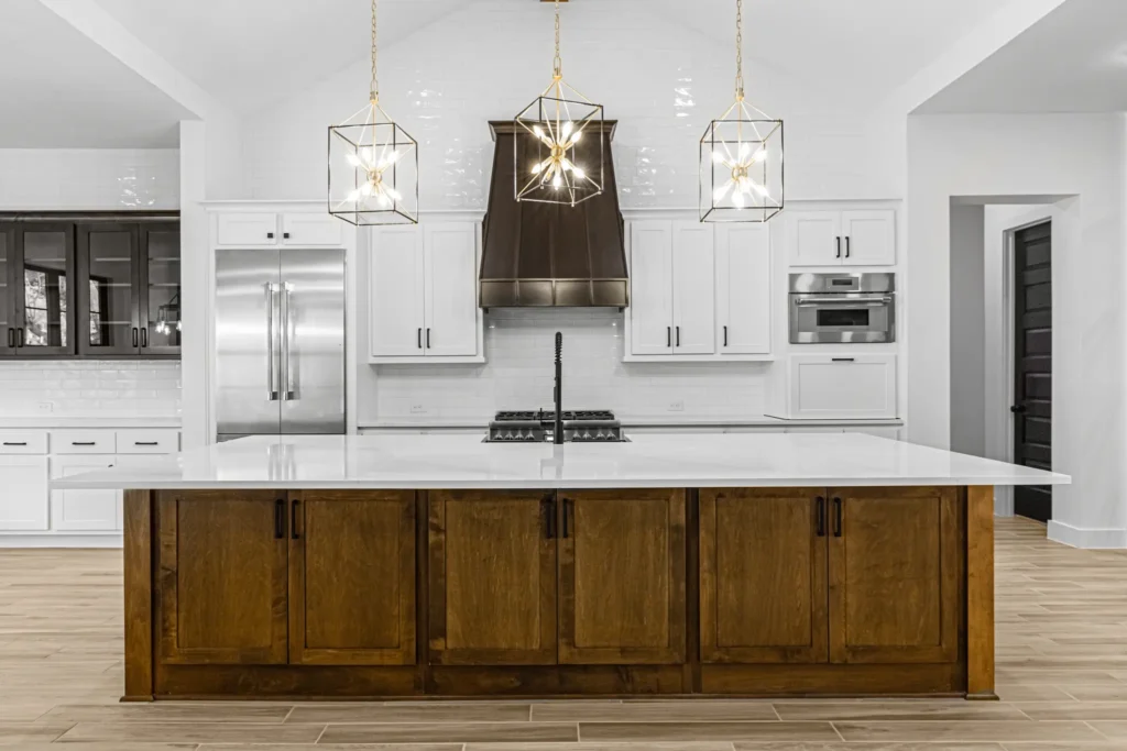 Custom home kitchen with wood cabinetry, white counters and three pendant lights