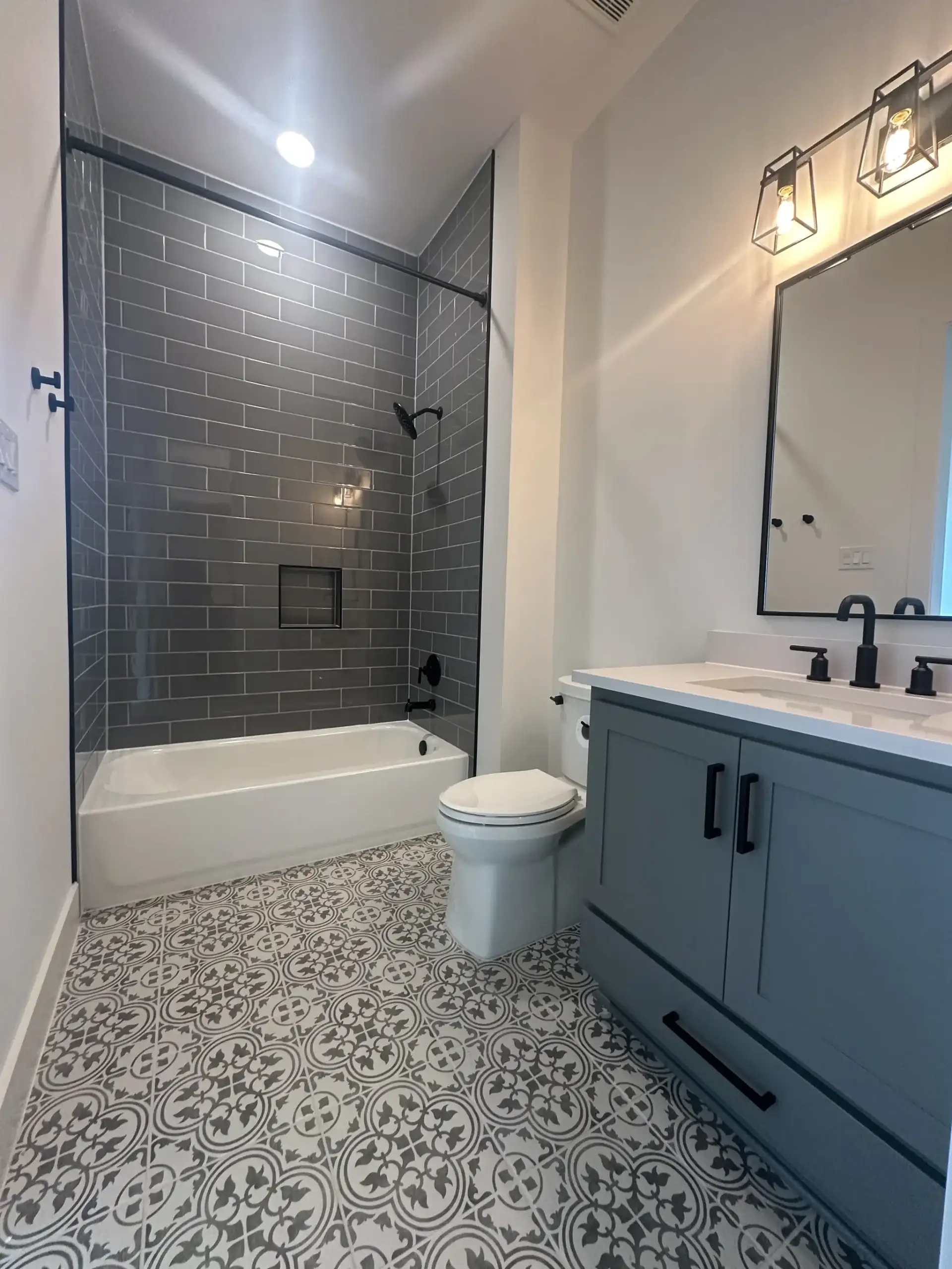 Custom home bathroom with a tiled tub-shower, patterned floor tile and a blue vanity