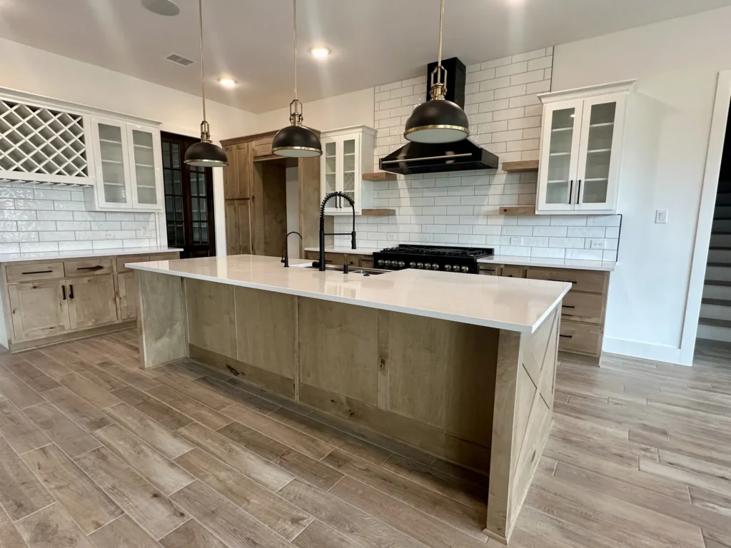 Custom home kitchen with a wood island, black range hood and subway tile backsplash