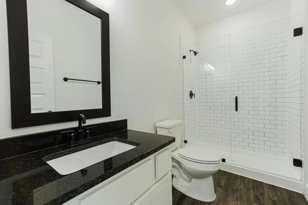 Custom home bathroom with a tiled walk-in shower and a dark-top vanity