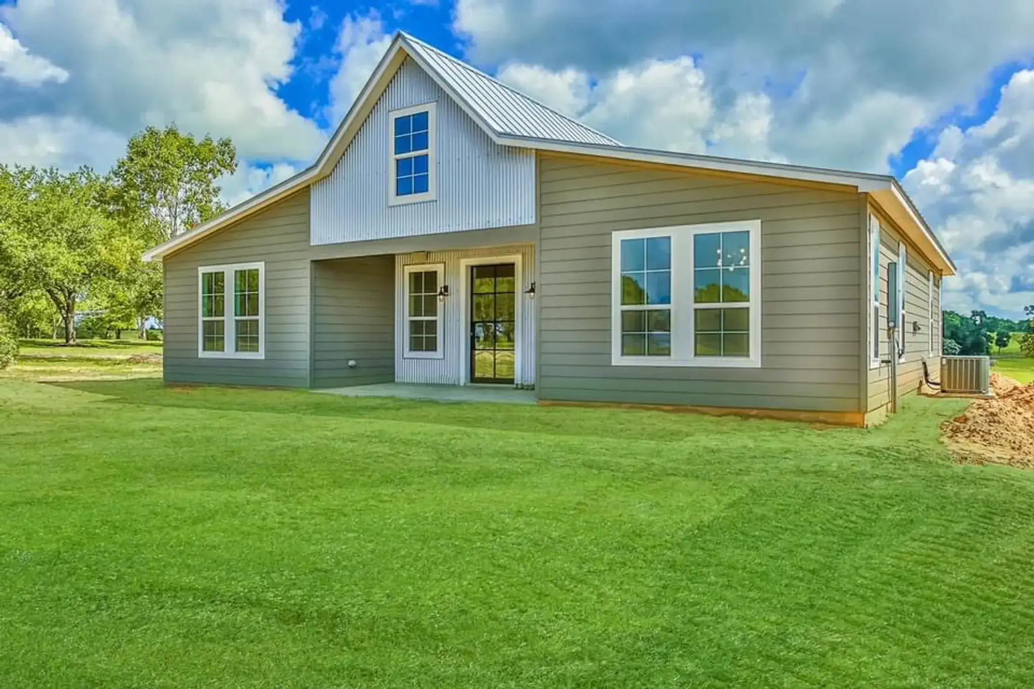 Custom-built sage-green two-story farmhouse with white-trimmed windows and a gabled roof