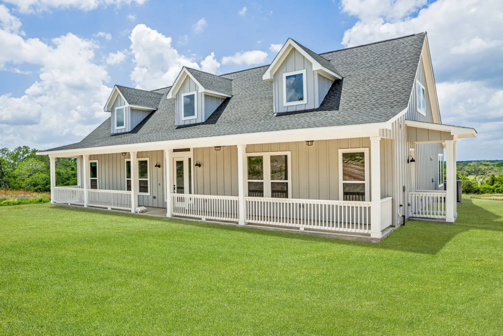 Custom-built cream single-story home with dormers and a white-railed front porch