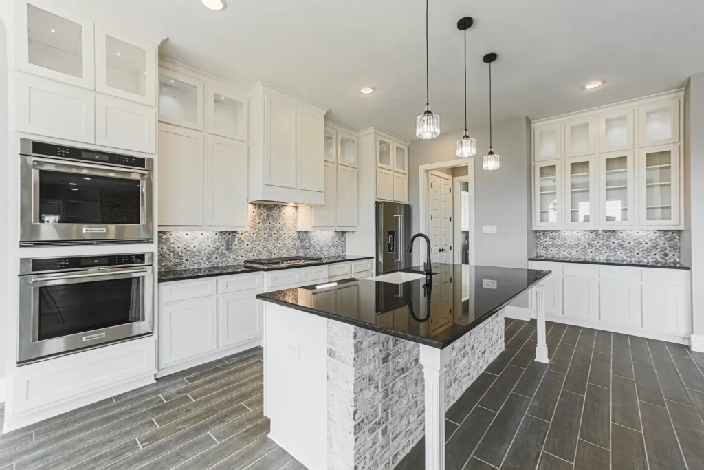 Custom home kitchen with white cabinets and a dark island with a waterfall stone countertop