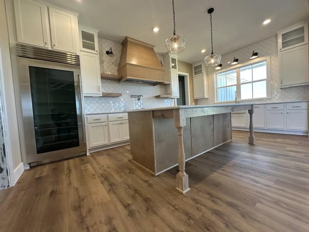 Open-concept custom home kitchen with a center island, wood range hood and pendant lights
