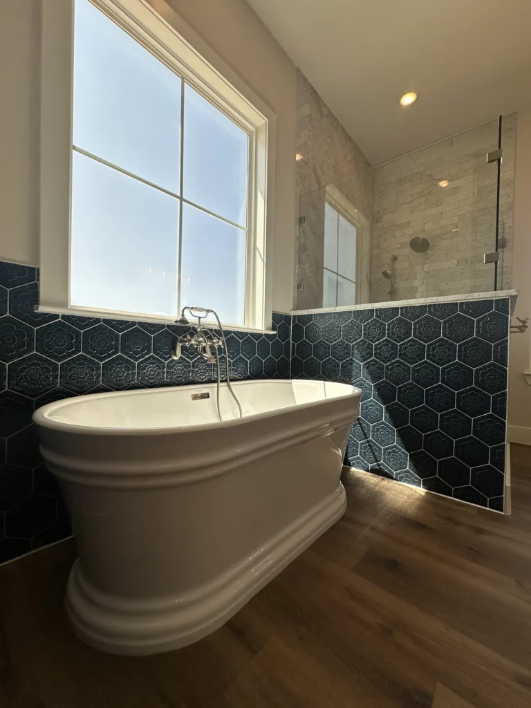 Custom home bathroom with a freestanding tub and a dark teal hexagon tile accent wall