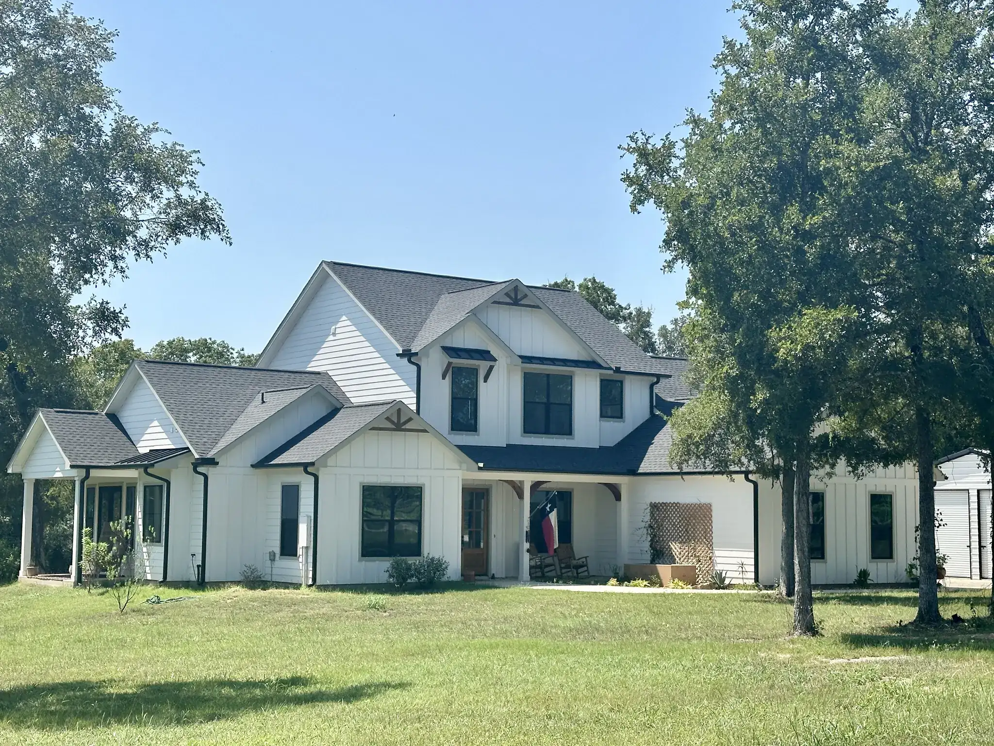 Two-story white modern farmhouse custom home with a covered porch and attached garage