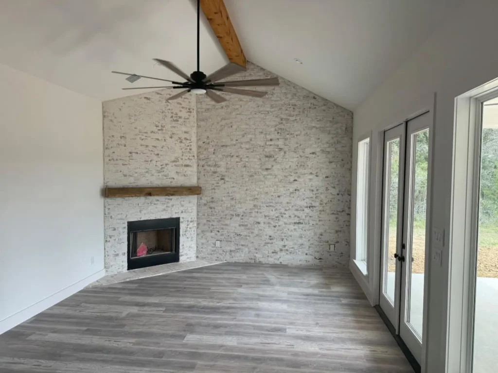 Custom home living room with a stone fireplace and a vaulted beam ceiling