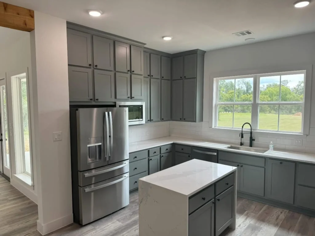 Custom home kitchen with sage-gray cabinets and a stainless French-door refrigerator