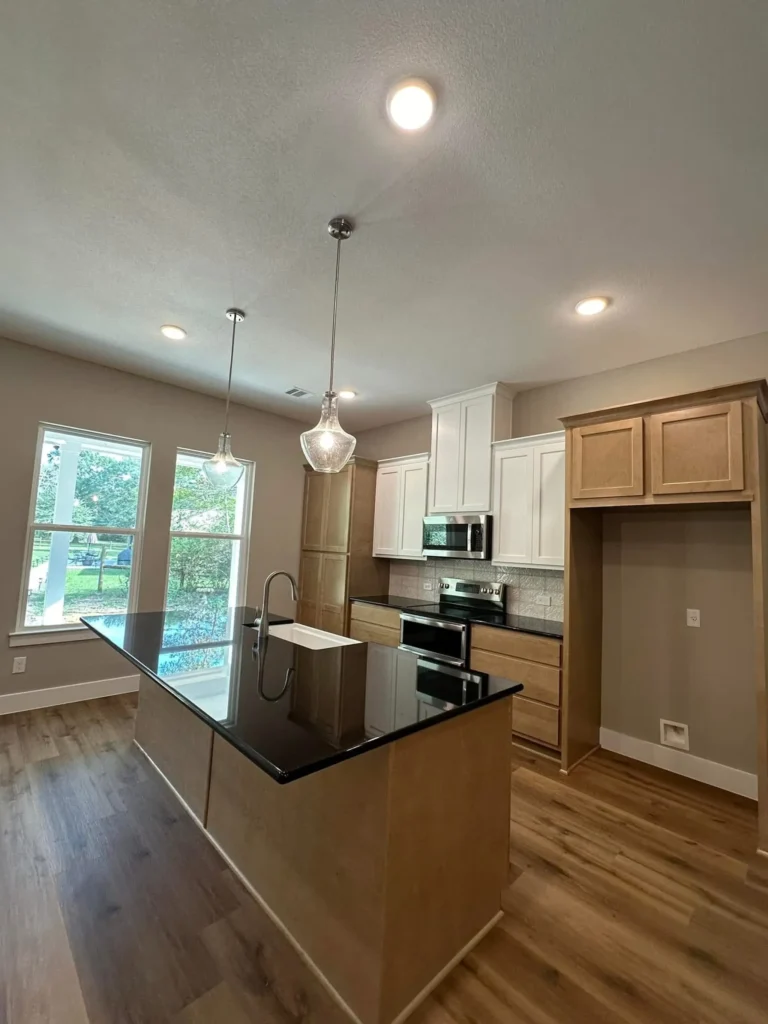 Custom home kitchen with a black island, mixed cabinetry and a large picture window