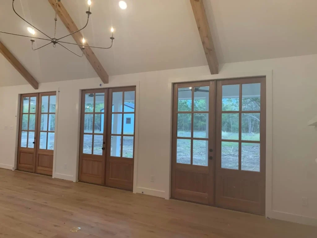 Custom home great room with a vaulted beam ceiling, French doors and a chandelier