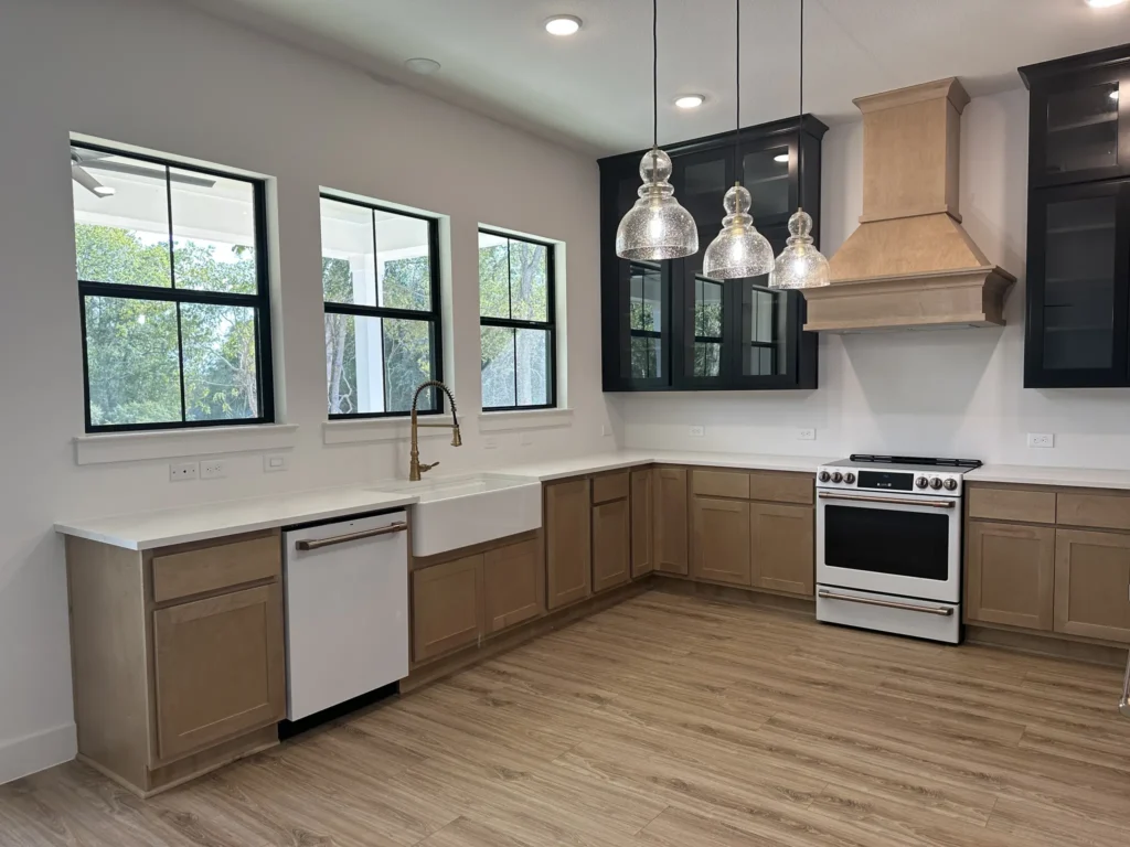 Custom home kitchen with dark cabinetry, a wood range hood and pendant lighting