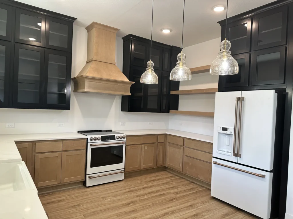 Custom home kitchen with dark upper cabinets, a wood range hood and a stainless range
