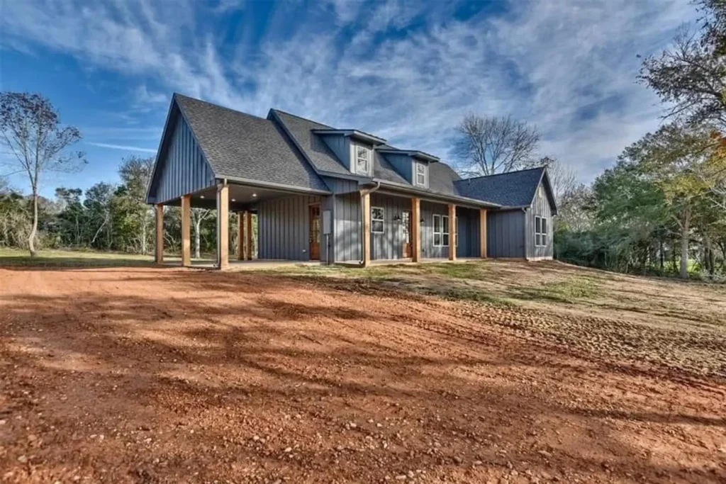 Custom modern farmhouse under construction with dark gables and stone porch columns