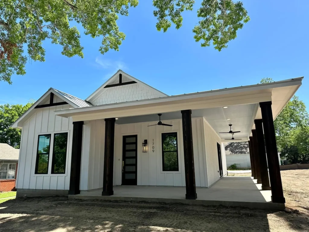 Front entry of a custom home with dark porch columns and a covered breezeway