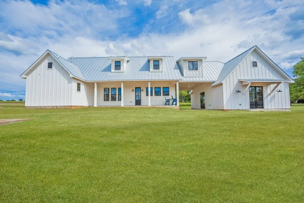 Custom-built white farmhouse with metal roof accents and a covered front porch