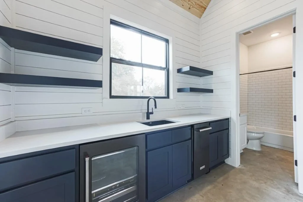 Custom home bathroom with blue cabinetry, open wood shelving and a window