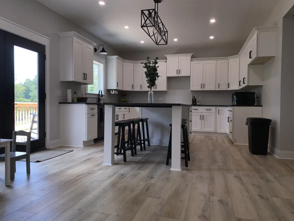 Custom home kitchen with a white island, black pendant lighting and an open layout