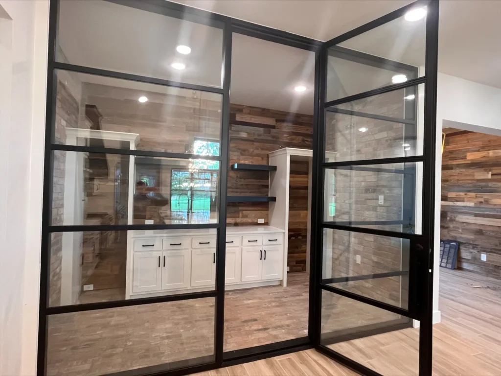 Custom home interior with a black-framed glass partition wall and wood flooring