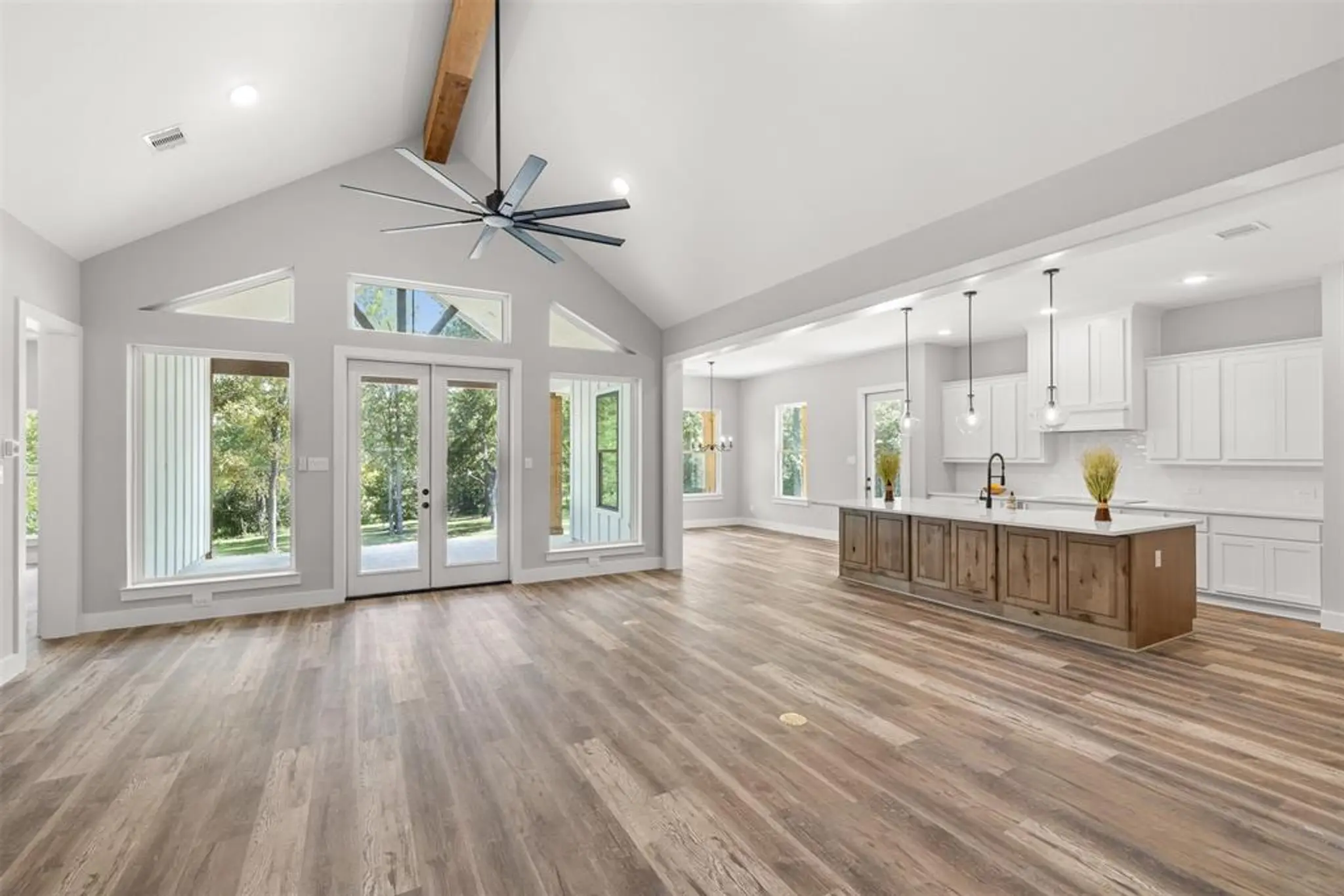Custom home great room with a vaulted wood-beam ceiling open to the kitchen