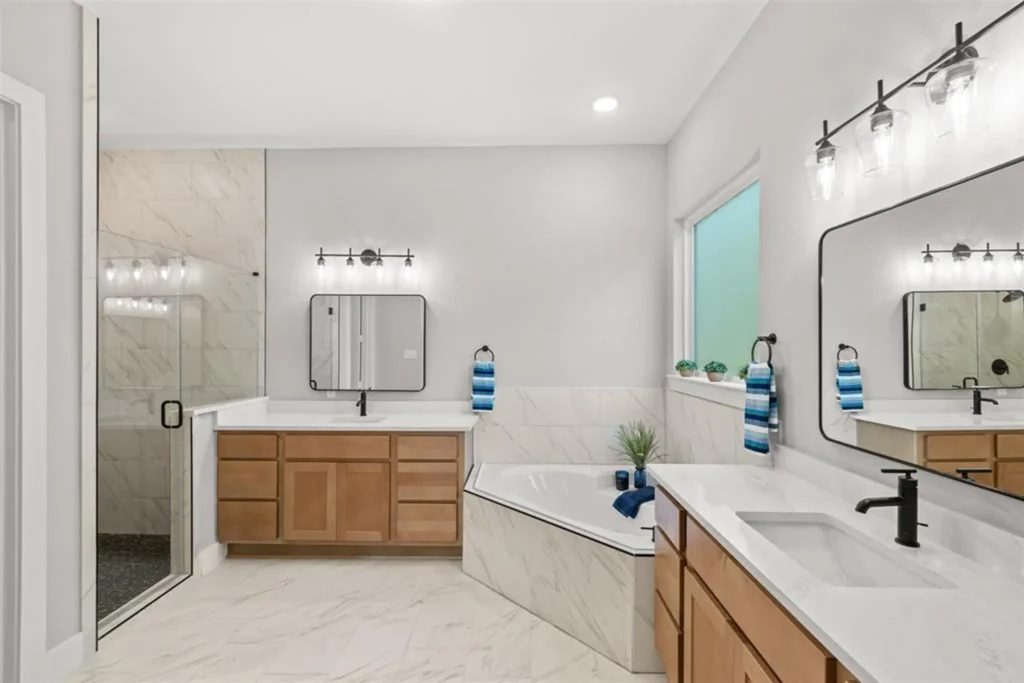 Custom home bathroom with a corner soaking tub, wood vanity and framed mirror