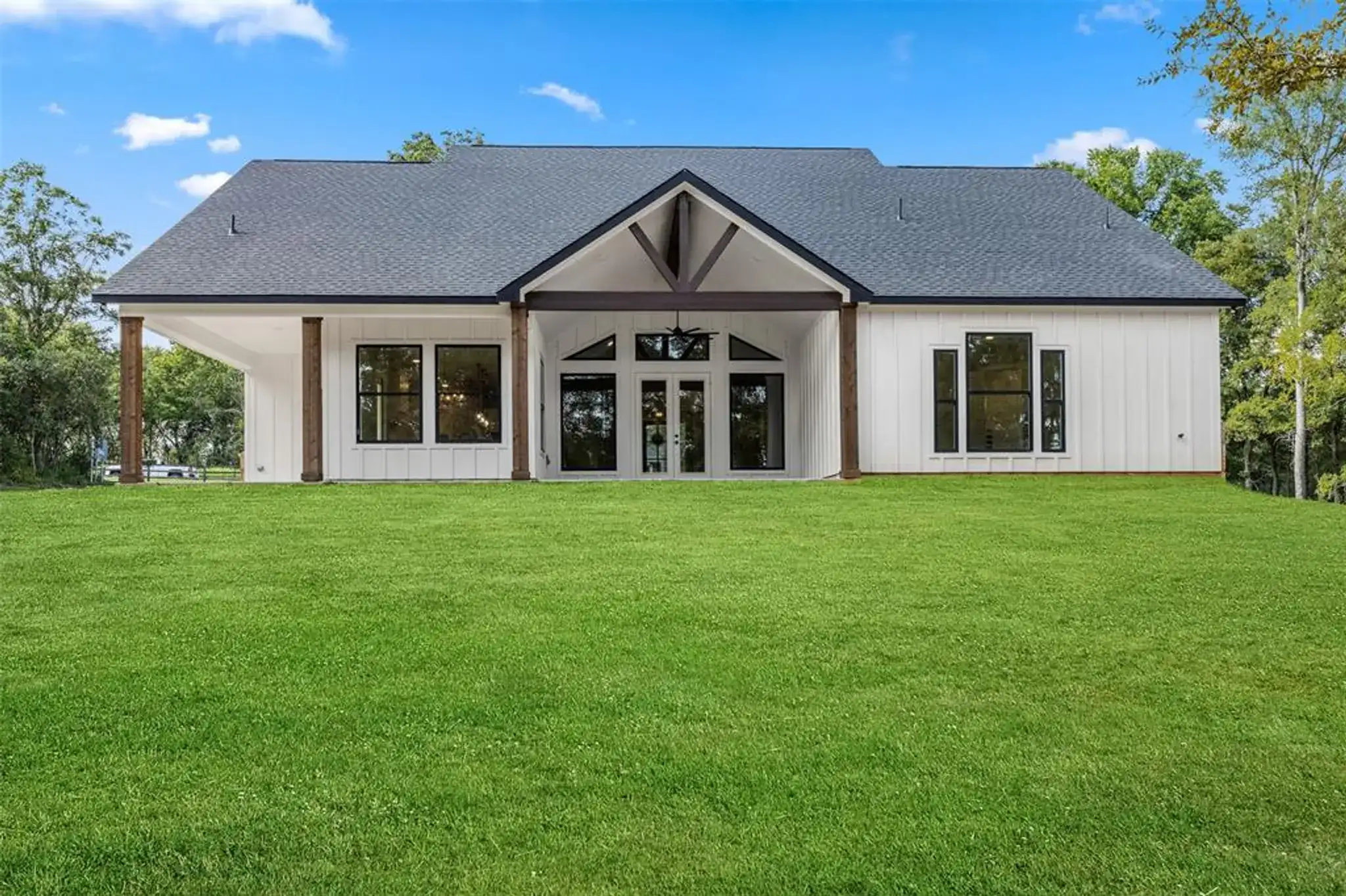 Custom-built modern farmhouse with white siding, dark trim and a gabled entry